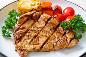 Grilled and barbecued fillet pork steak with corn, carrot, and tomatoes photo