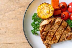 Grilled and barbecued fillet pork steak with corn, carrot, and tomatoes photo