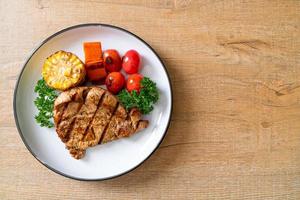 Grilled and barbecued fillet pork steak with corn, carrot, and tomatoes photo