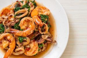 mariscos salteados de camarones y calamares con albahaca tailandesa - estilo de comida asiática foto
