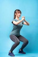 Young Asian woman wearing gym suit on blue background photo