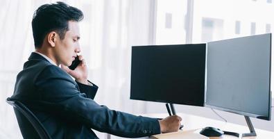 empresario asiático centrado en trabajar mientras habla por teléfono