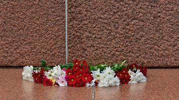 Letonia 100 años. Composiciones de flores rojas y blancas en el monumento a la libertad en la ciudad de Riga, Letonia. foto