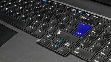 Computer notebook keyboard with blue 2020 key - holiday technology concept photo