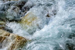 poderoso flujo de agua sobre las piedras, río de montaña de cerca. foto