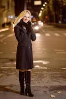 mujer hermosa, rubia en las luces del coche en la ciudad de noche. foto