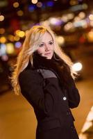 Beautiful, blonde woman in car lights in the night city. photo