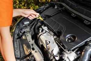 Car problems. The woman checks the engine oil level. photo