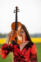 Portrait of a positive young woman. Part of the face is covered by the neck of the violin - image photo