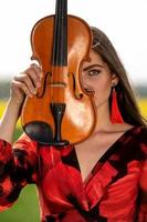 Portrait of a positive young woman. Part of the face is covered by the neck of the violin - image photo