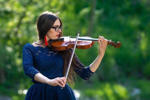 mujer joven tocando el violín en el parque. poca profundidad de campo - imagen foto