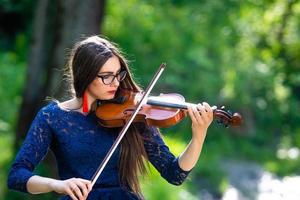Young woman playing the violin at park. Shallow depth of field - image