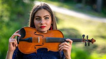 Portrait of a positive young woman. Part of the face is covered by the neck of the violin - image photo