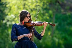 mujer joven tocando el violín en el parque. poca profundidad de campo - imagen foto