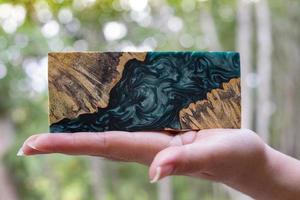 Hand holding epoxy resin Stabilizing Afzelia burl exotic wood red lava background photo
