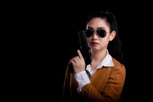 Asea woman wearing a yellow suit one hand holding a pistol gun at black background photo