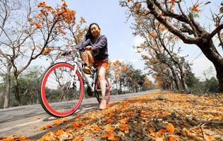 Young woman happy enjoying the outdoor leisure activity riding a bike and smiling for happiness the healthy lifestyles at full of beautiful orange flower background photo