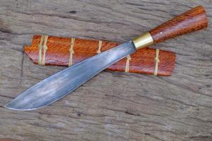 knife custom or Enep in the natural wood scabbard on old table background handmade of Thailand photo