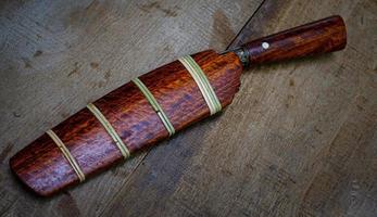 knife custom or Enep in the natural wood scabbard on old table background handmade of Thailand photo