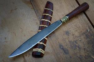 knife custom or Enep in the natural wood scabbard on old table background handmade of Thailand photo