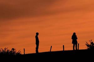 silueta de una pareja de trekking en el monte con una puesta de sol foto