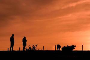 silueta de una pareja de trekking en el monte con una puesta de sol foto