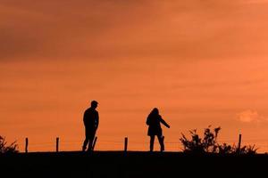 silueta de una pareja de trekking en el monte con una puesta de sol foto