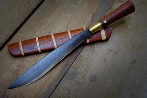 Cuchillo personalizado o enep en la vaina de madera natural sobre fondo de mesa antiguo hecho a mano de Tailandia foto