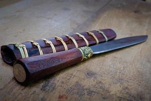 knife custom or Enep in the natural wood scabbard on old table background handmade of Thailand photo