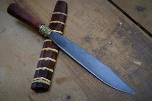 knife custom or Enep in the natural wood scabbard on old table background handmade of Thailand photo