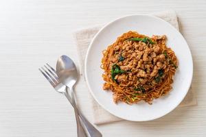 fideos instantáneos salteados con albahaca tailandesa y carne de cerdo picada - estilo de comida asiática foto