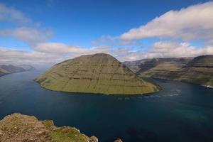 Camine por la montaña klakkur con un gran paisaje de fiordos panorámicos y pintorescos sobre las islas feroe foto