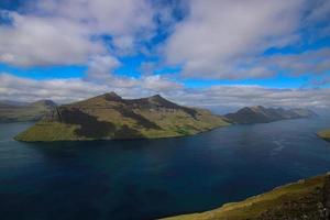 Camine por la montaña klakkur con un gran paisaje de fiordos panorámicos y pintorescos sobre las islas feroe foto