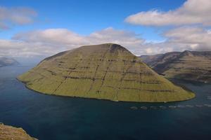 Camine por la montaña klakkur con un gran paisaje de fiordos panorámicos y pintorescos sobre las islas feroe foto