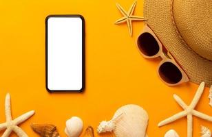 Summer background with blank screen phone and beach accessories, mask to prevent covid-19 on vibrant orange background top view with copy space. photo