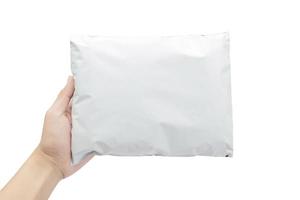 Mano sujetando el paquete de plástico blanco aislado sobre fondo blanco con trazado de recorte foto