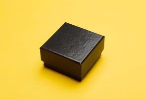 Embalaje de caja negra sobre fondo amarillo. foto