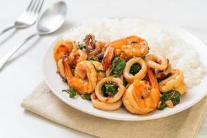 Rice and stir-fried seafood of shrimp and squid with Thai basil - Asian food style photo