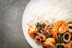 Rice and stir-fried seafood of shrimp and squid with Thai basil - Asian food style photo