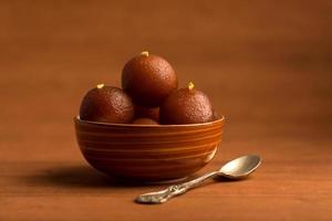 Gulab Jamun in bowl on wooden background. Indian Dessert or Sweet Dish. photo