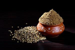 Coriander seeds and Powdered coriander in clay pot on wooden background. photo