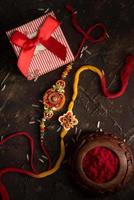 Raksha Bandhan background with an elegant Rakhi, Rice Grains, Kumkum and gift box. A traditional Indian wrist band which is a symbol of love between Brothers and Sisters. photo