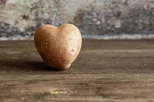 Patata roja en forma de corazón sobre fondo vintage.El concepto de agricultura, cosecha, vegetarianismo. día de San Valentín. comida cuadrada y fea. foto