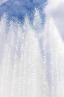 Background of water jets and fountain splashes against a blue sky with clouds photo