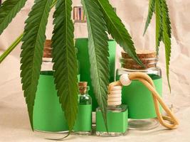 Cosmética natural con cannabis y botellas verdes y hojas de marihuana. foto