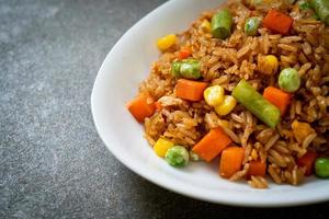 arroz frito con guisantes, zanahorias y maíz - estilo de comida vegetariana y saludable foto