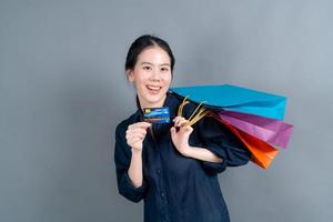 Hermosa mujer asiática con bolsas de la compra y mostrando tarjeta de crédito foto