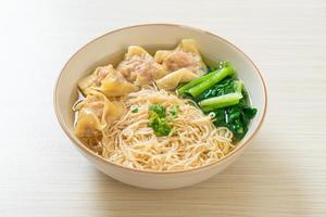 Egg noodles with pork wonton soup or pork dumplings soup and vegetable - Asian food style photo