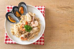 Pasta espiral con salsa de crema de champiñones y mariscos - estilo de comida italiana foto