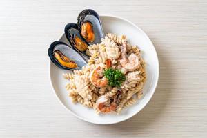 Pasta espiral con salsa de crema de champiñones y mariscos - estilo de comida italiana foto